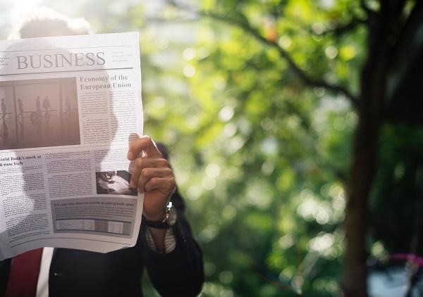 Man reads newspaper at park