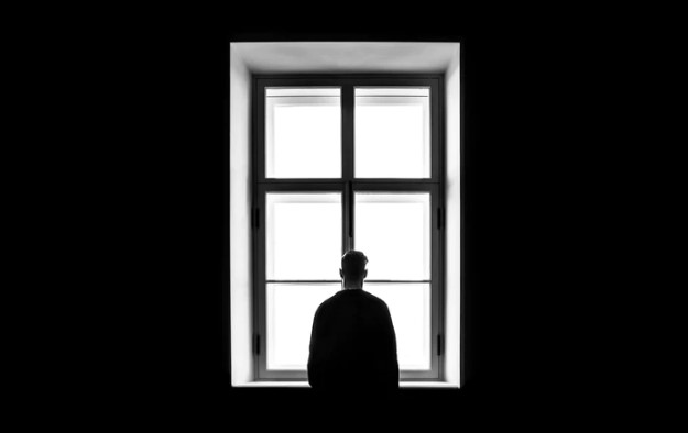 Man standing in a black room by window